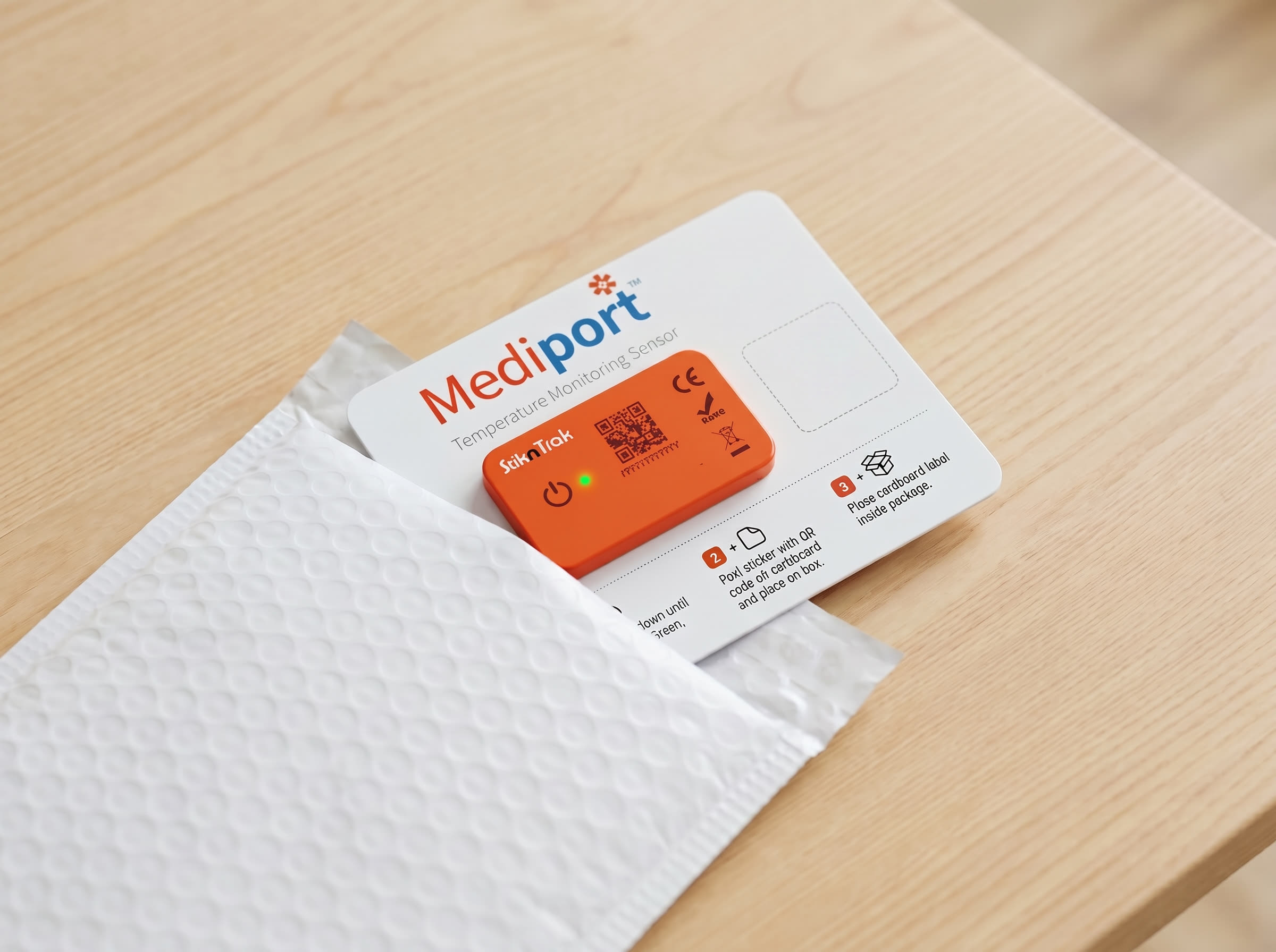 A single Mediport-branded StiknSense instruction card being slid into the open top of a white padded courier bubble mailer on a wooden table