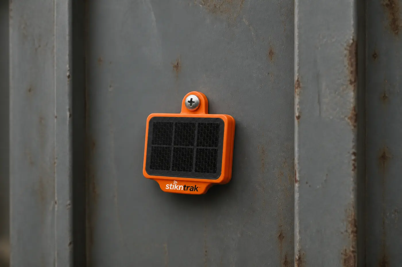 Compact orange StiknTrak Intermodal Asset Tracker mounted on a container